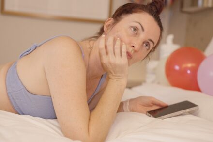 AO Scan Woman lying on bed with phone and balloons