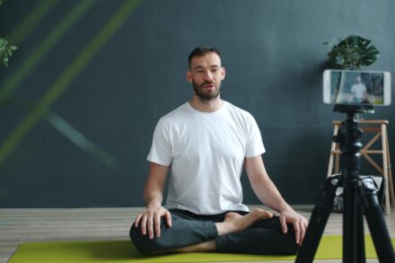 Chakra Healing Man meditating on yoga mat recording with phone.