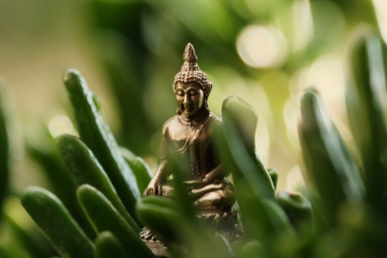 a small buddha statue sitting in the middle of some grass