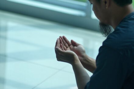 a man sitting on the ground with his hands together