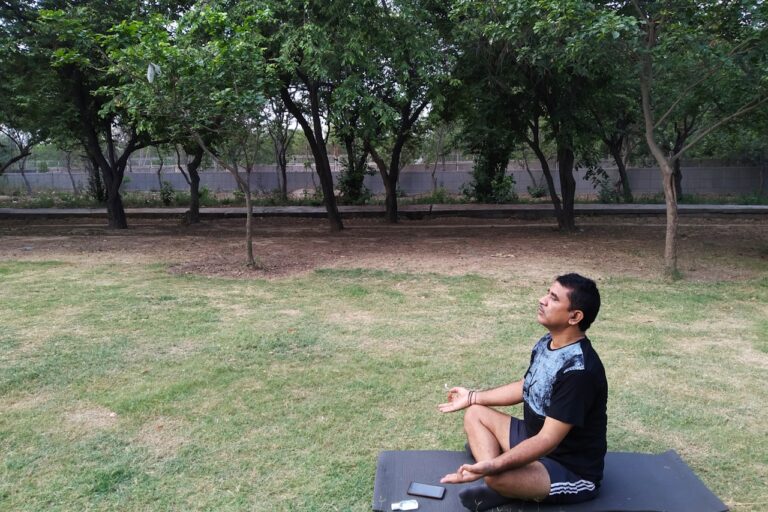 man in blue crew neck t-shirt sitting on gray wooden bench during daytime