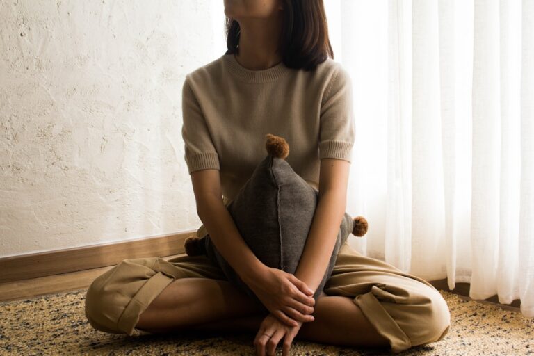 Emotional Healing woman in white knit sweater sitting on brown wooden seat