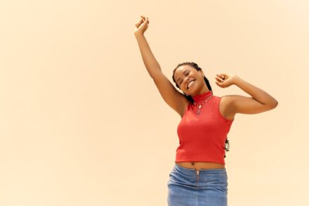 A woman in a red shirt and blue skirt holding a white frisbee