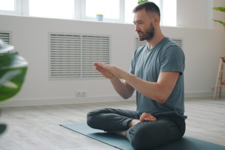 Man meditating in a bright, minimalist room.