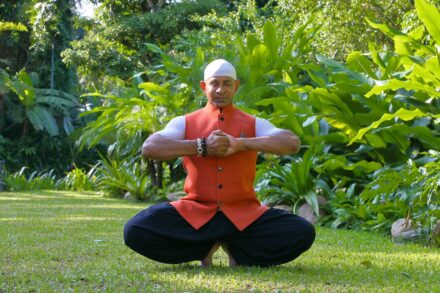 A man in a red shirt and black pants doing yoga