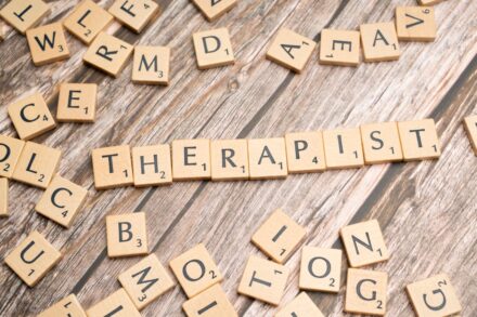 scrabble tiles spelling out the word therapy on a wooden surface