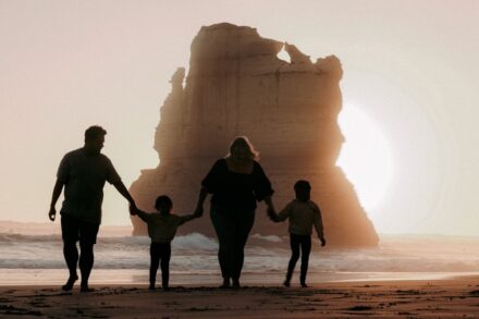 a family walking on the beach at sunset
