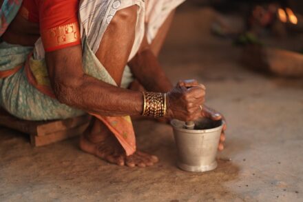 Elderly hands grinding spices in a mortar and pestle.