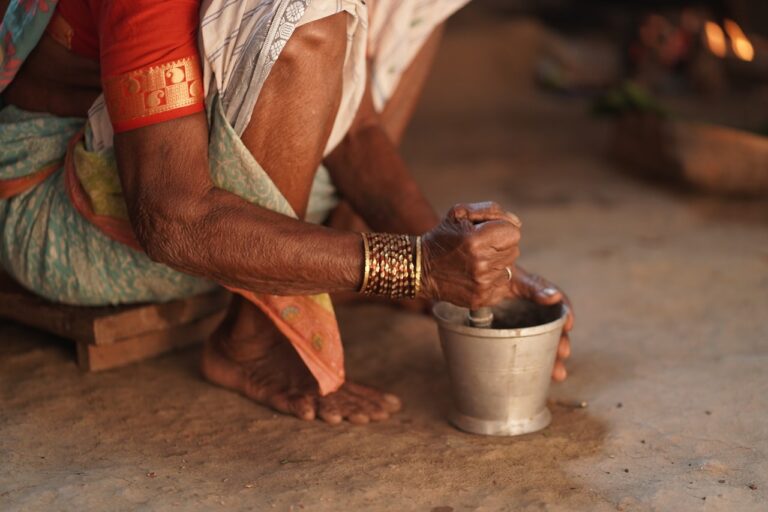 Elderly hands grinding spices in a mortar and pestle.