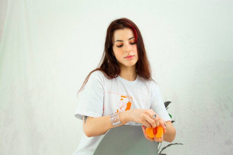 Crystal Healing woman in white crew neck t-shirt holding orange fruit