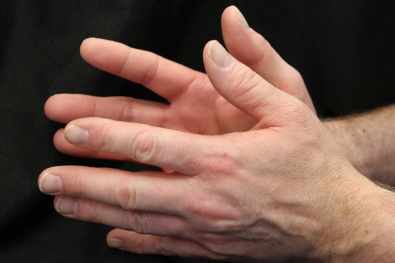 Hands pressing into the palm using a hand reflexology self-healing technique