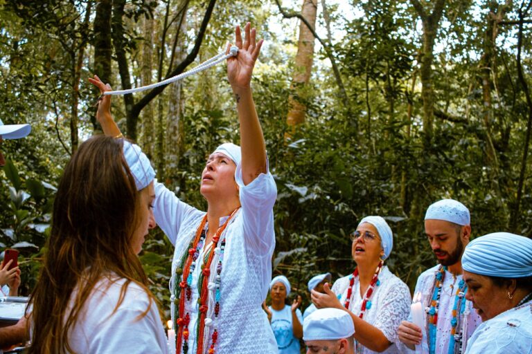 Group in white clothing performing ritual in forest.