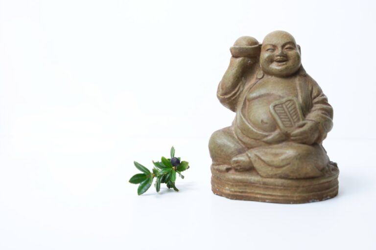 a small statue of a person holding a cell phone next to a small plant