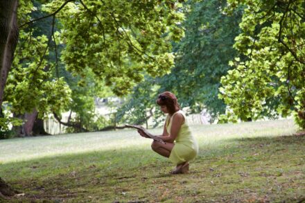 Holistic Healing a woman in a yellow dress crouches in the grass