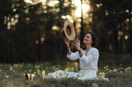 Holistic Healing a woman sitting in a field with a hat