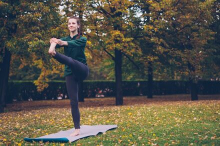 Holistic Healing Woman practicing yoga on mat in autumn park
