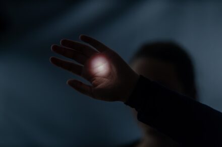 a person holding their hand out in the dark