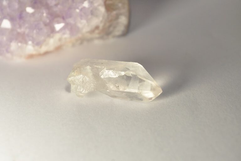 A clear crystal with purple quartz in the background.