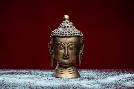 gold buddha figurine on white and blue textile