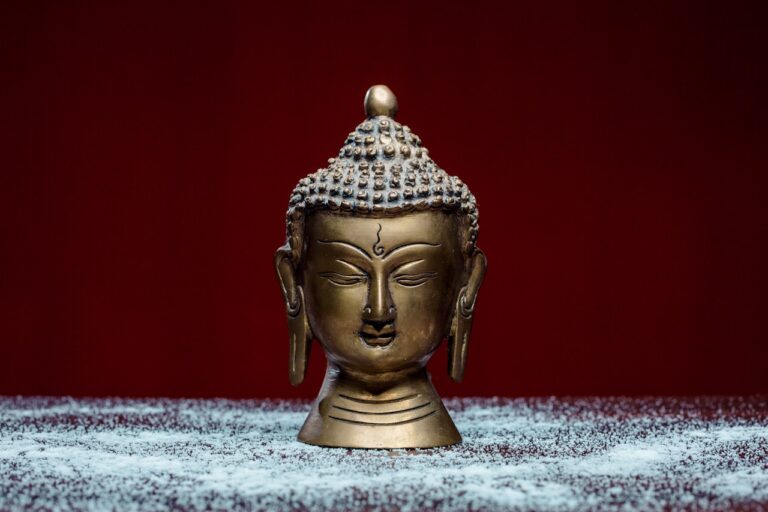 gold buddha figurine on white and blue textile