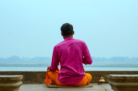 A man in a pink shirt sitting on a ledge