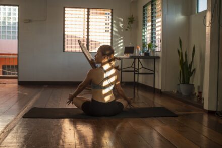 woman in white tank top and black shorts sitting on brown wooden floor