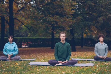 Mind-Body Healing Three people meditating in a park during autumn.