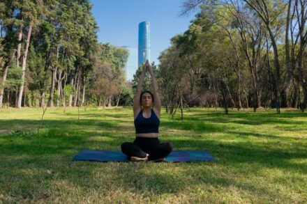 Mind-Body Healing Woman meditating on a yoga mat in a park.
