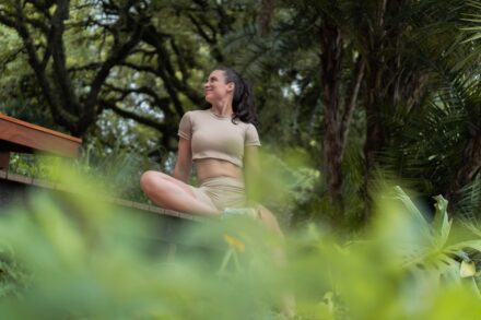 Mind-Body Healing A woman meditating outdoors amidst lush greenery.