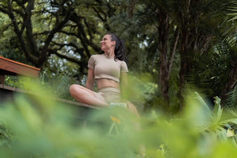 Mind-Body Healing A woman meditating outdoors amidst lush greenery.
