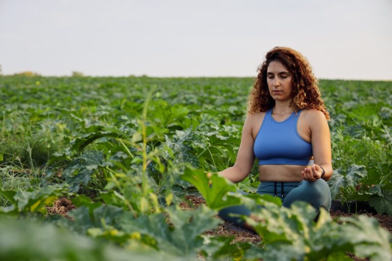 Mind-Body Healing woman in blue sports brassiere meditating on plant field