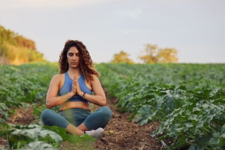 Mind-Body Healing woman sitting on ground while meditating and surrounded by plant field in macro photography
