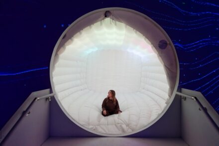 Woman sits inside a glowing circular structure.