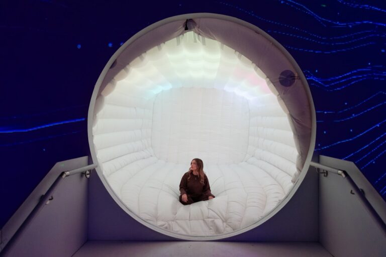 Woman sits inside a glowing circular structure.