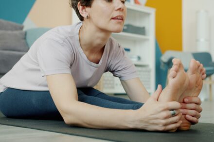 Physical Healing Woman stretching her legs on a yoga mat.