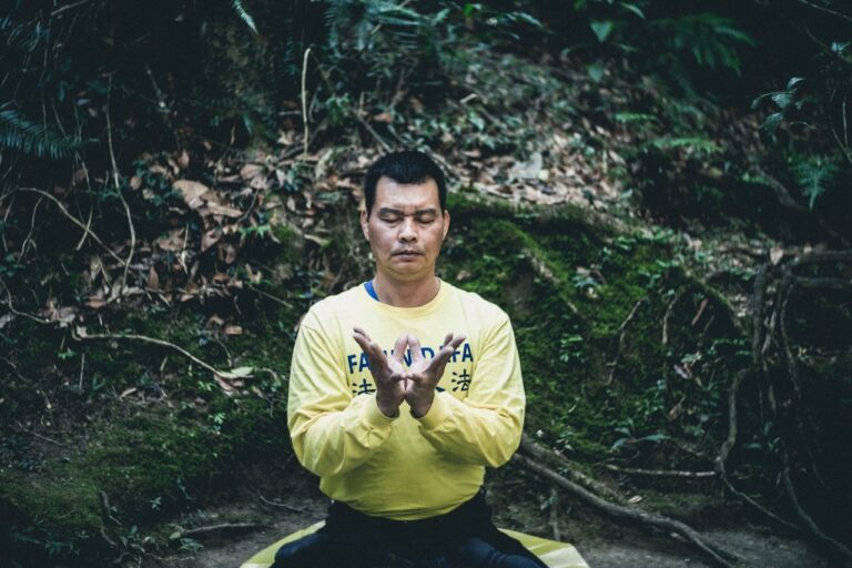 man meditating under forest