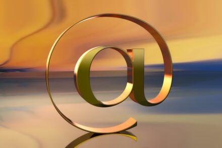 A golden @ symbol against a colorful backdrop.