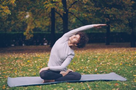 Quantum Healing & Techniques Woman stretching on yoga mat in park