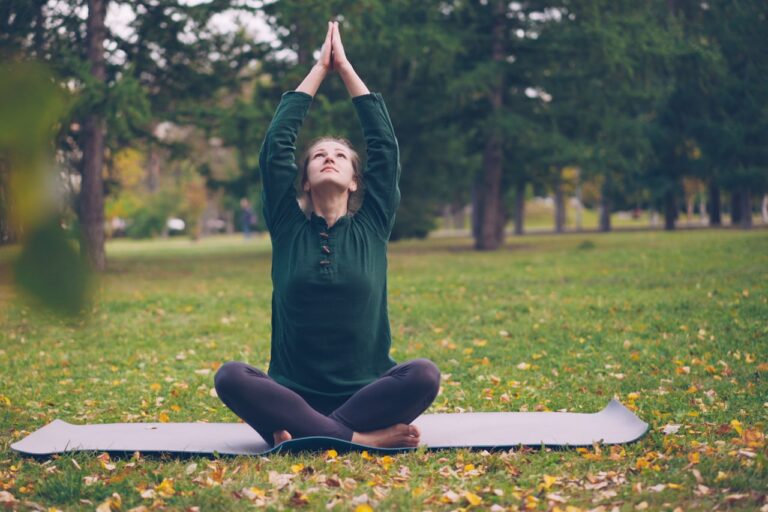 Quantum Healing & Techniques Woman meditating in a park with arms raised