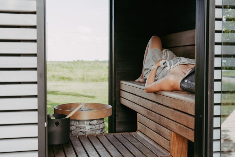 Quantum Healing & Techniques Person relaxing in a wooden sauna with outdoor view.