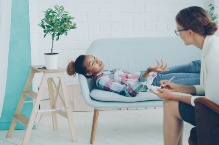 Quantum Healing & Techniques A young girl talks to a therapist on a couch.