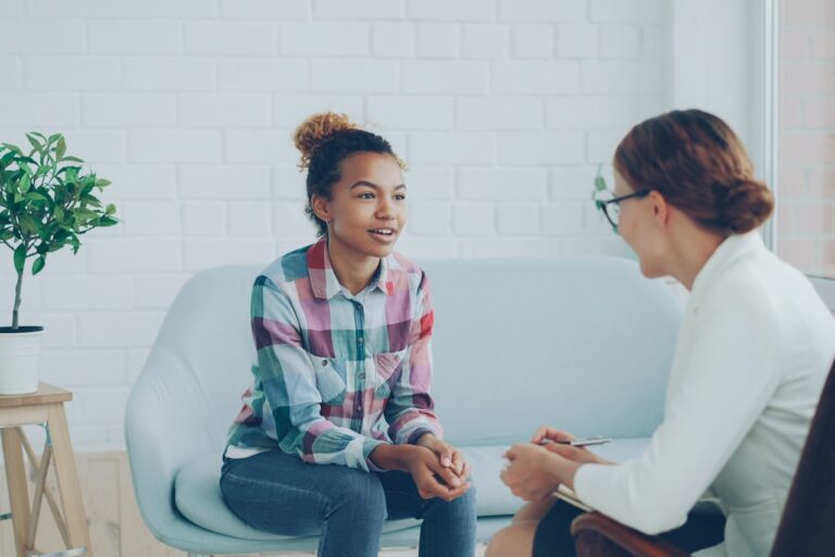 Quantum Healing & Techniques Two women talking in a modern office setting.