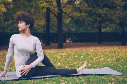 Quantum Healing & Techniques Woman practicing yoga on mat in park
