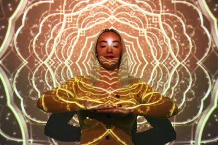 Quantum Healing & Techniques a woman in a yellow outfit is standing in front of a glowing background