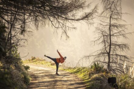 woman in white dress walking on pathway between bare trees during daytime
