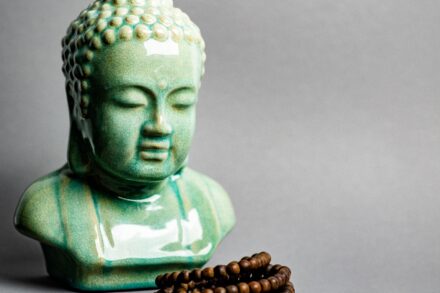 A buddha statue next to a beaded bracelet