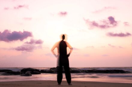 silhouette of woman standing on beach during sunset