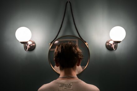 rTMS (Repetitive Transcranial Magnetic Stimulation) boy in white tank top standing in front of black and white wall lamp