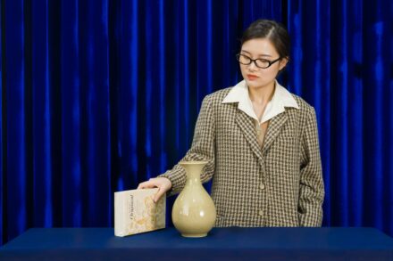 Aromatherapy Woman in blazer examines vase and book.