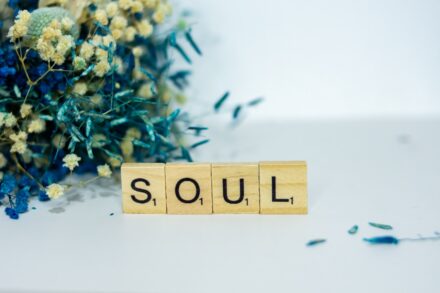 a wooden block spelling the word soul next to a bouquet of flowers